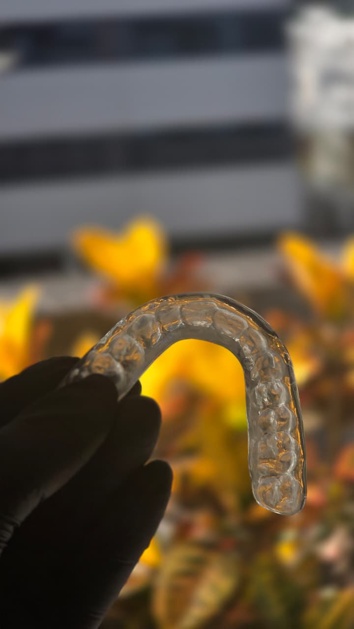Placa miorrelaxante transparente fresada, segurada por mão com luva