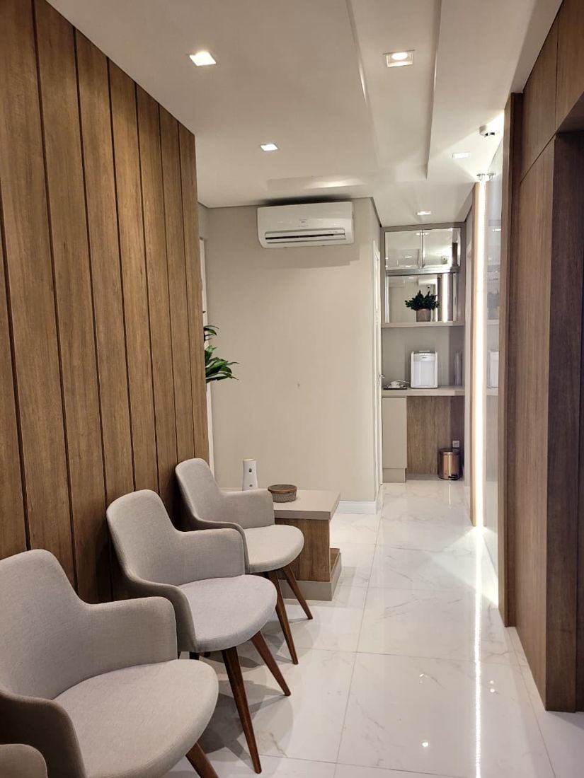 Sala de espera com poltronas e painel de madeira ripada